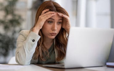 Frustrated female ABA provider holding head looking at laptop