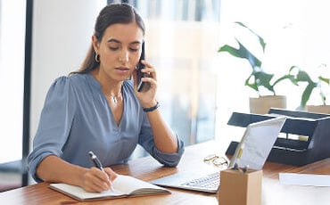 Female ABA provider writing while on phone call in practice